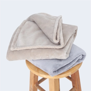 Soft flannel blankets in grey and beige colors stacked on a wooden stool