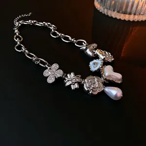 Silver link necklace with pearl heart and strawberry flower pendants on a dark surface