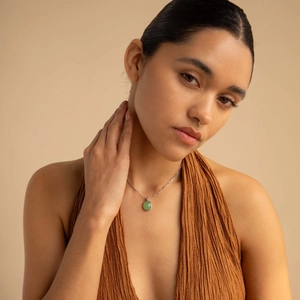 Double-layered gold necklace with a green aventurine stone pendant on a model