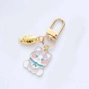 Close-up of a cartoon purple cat keychain with a small gold fish charm on a golden ring