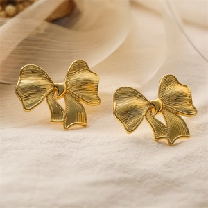 Macro shot of 18K gold plated bow earrings with metallic texture and pleated details