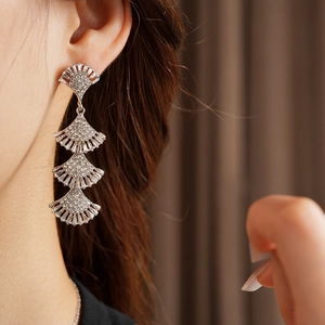 Detail of silver layered fan-shaped tassel earrings with rhinestones on model