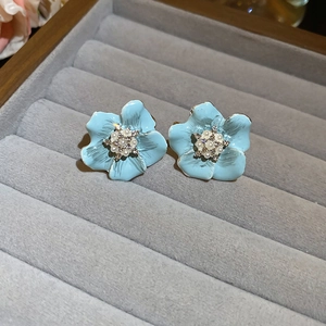 Macro de boucles d'oreilles fleurs bleu clair avec perles sur un plateau en velours