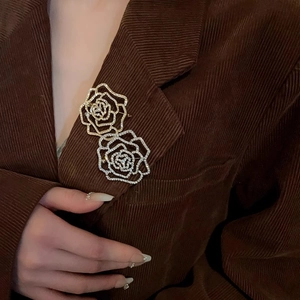 Elegant gold and silver flower brooches with cubic zirconia on brown corduroy suit jacket