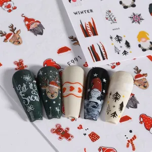 Christmas nail art stickers featuring reindeer, Santa, and snowflakes on five manicured nails