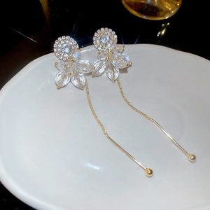 Detailed shot of long gold tassel earrings with crystals on a white ceramic plate