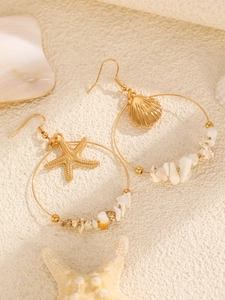 Detalle de pendientes de aro dorados con estrella de mar, concha y piedras naturales