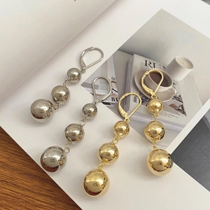 French style triple gold and silver metallic sphere drop earrings on a magazine background