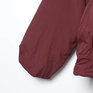 Detalle de chaqueta kimono rojo vino oscuro con tejido sintético premium y costura de manga