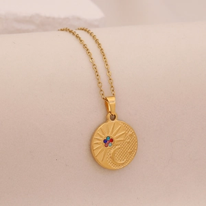 Macro shot of gold stainless steel sun and moon pendant with colorful cubic zirconia