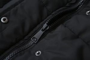 Dettaglio macro della cerniera in resina nera e bottone a pressione su gilet imbottito
