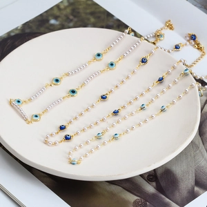 Elegant evil eye pearl necklace set with gold accents on a white decorative plate