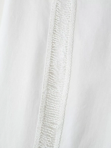 Détail de la dentelle blanche et de la broderie évidée complexe sur pantalon doux femme