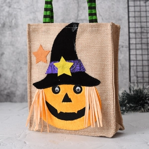 Detail of burlap Halloween candy bag featuring a pumpkin face and green striped handle