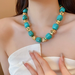Detail of turquoise irregular beads and gold metal accents on the bracelet wrist