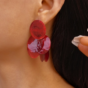 Close-up of vibrant red layered circular earrings worn by a model for a chic look