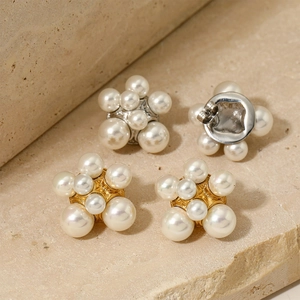 Elegant gold and silver floral pearl stud earrings on a textured stone background