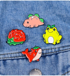 Creative enamel pins with cute animal-fruit designs displayed on a blue denim jacket