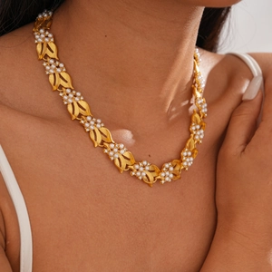 Close-up of golden leaf necklace with white pearls and zircons worn by a model