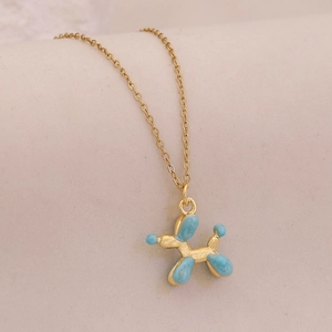 Detail of golden balloon dog pendant with blue marble texture on a delicate chain