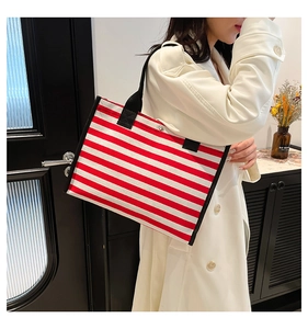 Model showcasing a red and white striped canvas tote bag with black strap handles