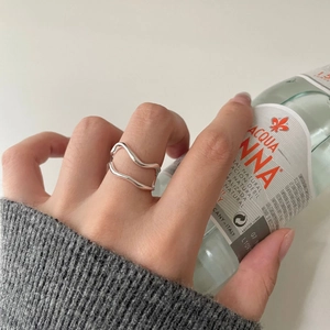Detail shot of 925 silver double-layered wavy open ring on hand holding a glass bottle