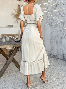 Detail view of the back of a white square neck dress with black scalloped edge ruffles