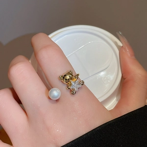 Detail of adjustable gold ring featuring a bear holding a star crystal and white pearl