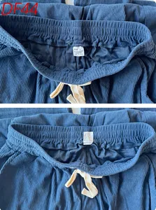 Detail of blue corduroy pants featuring an elastic waist with cream drawstring and size tag