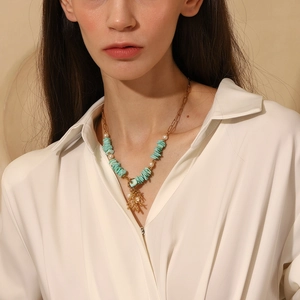 Detail of 18K gold plated necklace with coral pendant, turquoise stones and white pearls