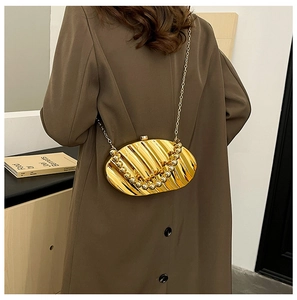 Detailed back view of gold shell-shaped acrylic evening bag with metallic chain strap