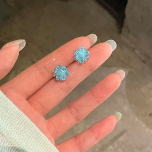 Detailed view of light blue resin flower stud earrings with subtle glitter finish