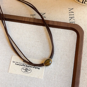 Detail of tiger eye stone necklace with dark brown cords and silver edge setting
