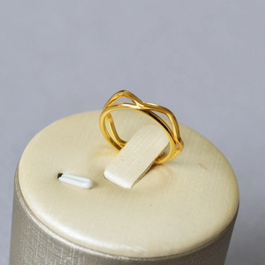 Close-up of minimalist wave pattern gold plated brass ring on jewelry cushion