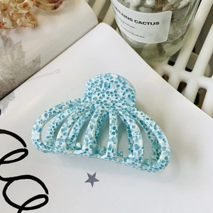 Détail d'une grande pince à cheveux en acétate à motif marbré sur un magazine