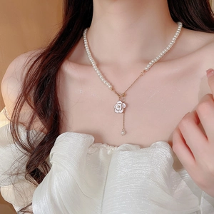 Detailed close-up of camellia flower pendant necklace with elegant pearl fringe on a model