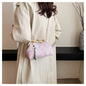 Elegant embroidered evening bag with tassel on a model in a beige trench coat