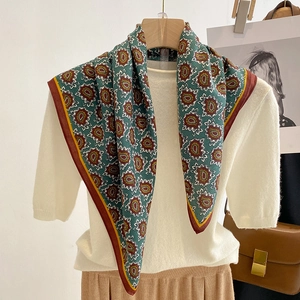 Detail of silk-feel paisley square scarf in dark green draped on a knitted top