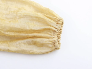 Détail de la manche lanterne en soie jacquard dorée avec poignet élastique de la robe