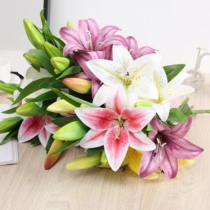 Detailed close-up of multi-colored silk lily flowers with realistic buds on a wooden table