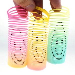 Three gradient plastic slinky toys with black smiley face prints held on white backdrop