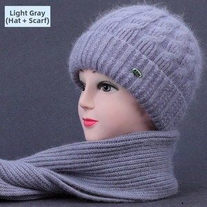 Detail of light grey knitted beanie and scarf set with thick cable knit texture and metal tag