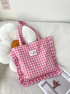 Detail of pink gingham tote bag featuring sweet ruffle edges and fun fun party text