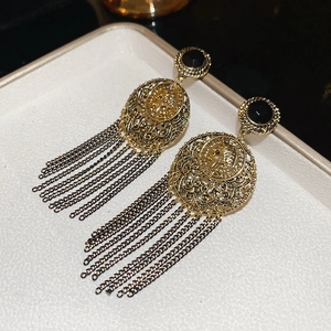 Detail view of vintage French style gold earrings with black tassels and coin relief