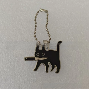 Detailed view of a black enamel cat charm holding a knife on a silver bead chain
