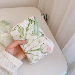 Close-up of a quilted floral mini pouch with pink roses and a green drawstring zipper pull