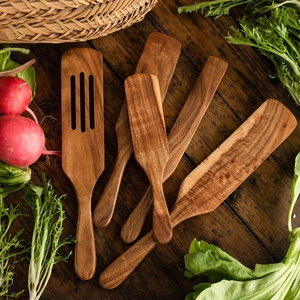 Rustic scene of teak wood cooking utensils and fresh vegetables on a wooden table