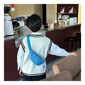 Blue nylon kids fanny pack shown worn as a crossbody chest bag in a cafe setting