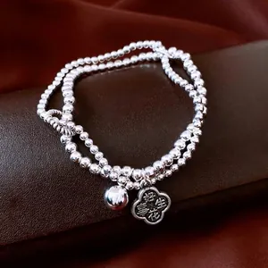 Elegant double-layered beaded bracelet with flower pendant and engraved silver charms