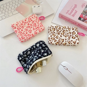 Three leopard heart print pouches displayed with a laptop, mouse and office accessories